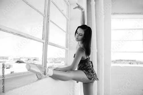 Ballerina stretching herself in a dancing studio. Black and white photo photo