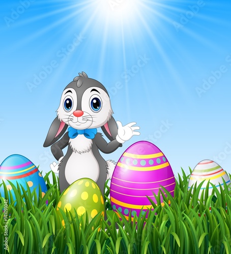 Easter bunny cartoon waving with easter eggs in the grass background 