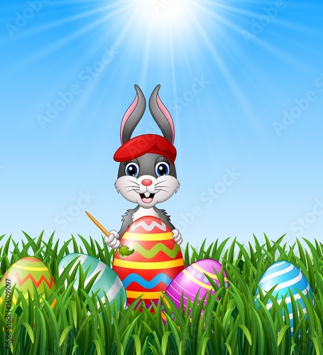 Easter bunny painting easter eggs in the grass background 