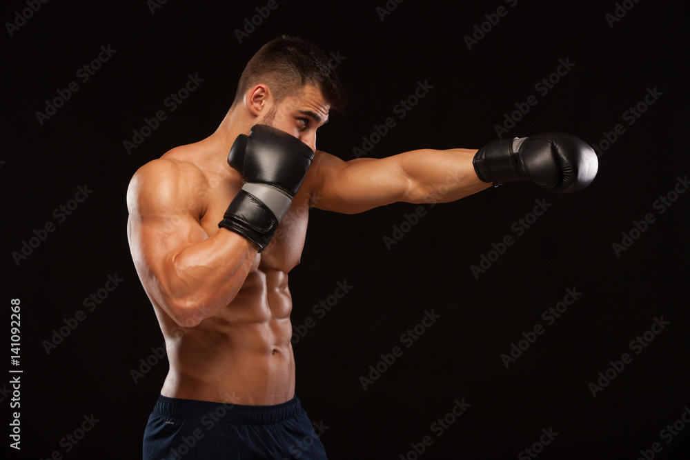 Muscular young man with perfect Torso with six pack abs, in boxing gloves is showing the different movements and strikes isolated on black background with copyspace Muscular young man with perfect Torso with six pack abs, in boxing gloves is showing the different movements and strikes isolated on black background with copyspace