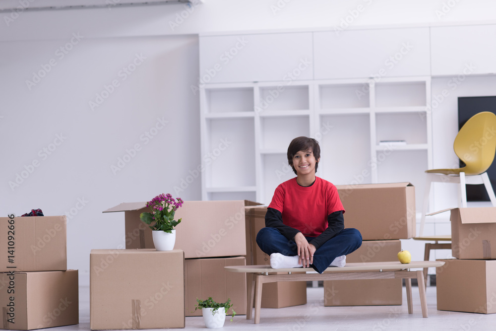boy sitting on the table with cardboard boxes around him boy sitting on the table with cardboard boxes around him