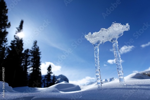 Natürliche Skulptur aus Eis mit blauem Himmel und Nadelbäumen.