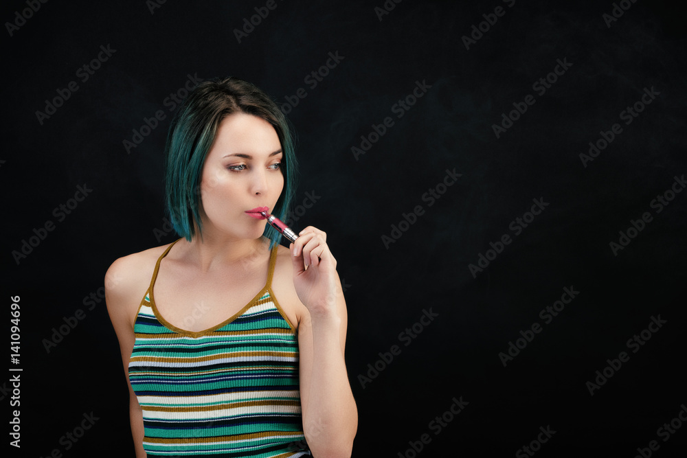 Obraz premium Jeune femme vape une cigarette électronique