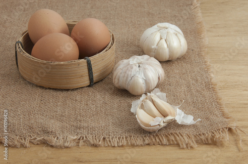 Prepared ingredients to cook. Garlic with brown chicken egg on table