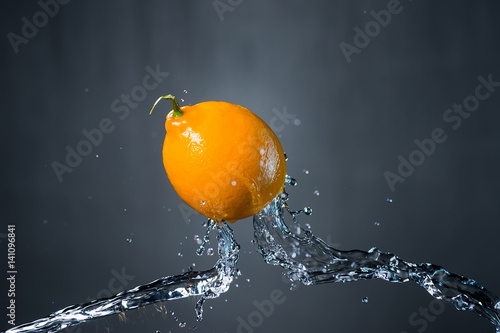 lemon and splash of water on gray background