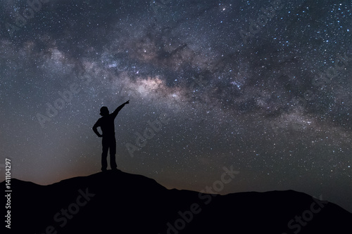 Milky Way landscape. Silhouette of Happy woman standing on top of mountain with night sky and bright star on background.