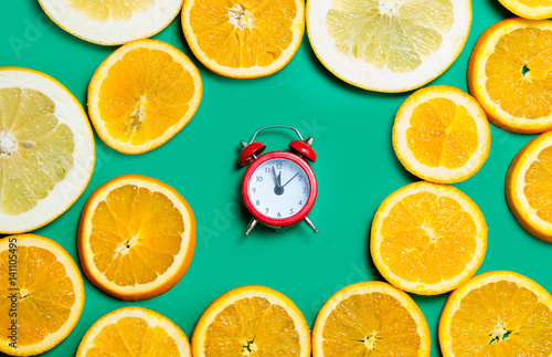 photo of cute alarm clock near dried orange slices on the wonderful turquoise background
