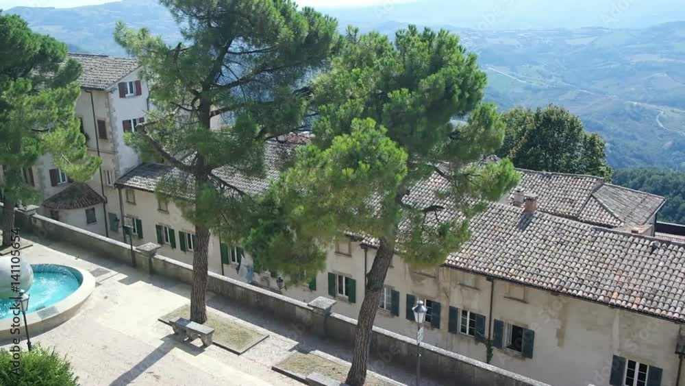 Panorama of San Marino and Italy from Monte Titano. View from the top of the Pyrenees mountains, roofs, pine trees and a fountain Panorama of San Marino and Italy from Monte Titano. View from the top of the Pyrenees mountains, roofs, pine trees and a fountain