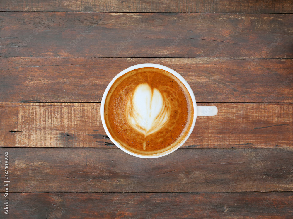 Top view of a coffee with heart pattern in a white cup on wooden plank background, latte art Top view of a coffee with heart pattern in a white cup on wooden plank background, latte art