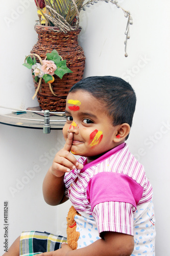 Silence Please. Portrait of a naughty little kid at Holi festival. He is enjoying the festival.