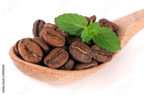 Coffee beans in a wooden spoon with leaf isolated on a white background