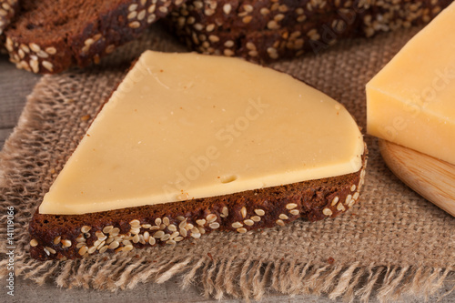 slices of black bread with sesame seeds and cheese on the old wooden background