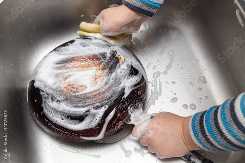 Fotografie boy washing dishes in the kitchen
