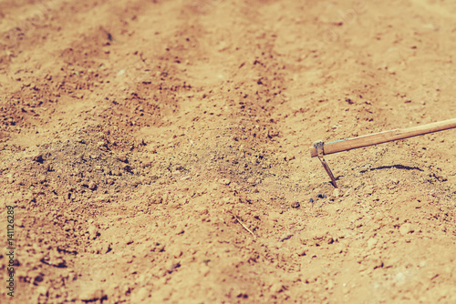 Freshly plowed field and mattock for manually planting in spring.