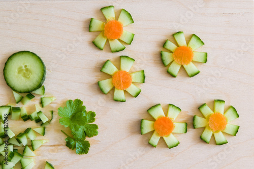 Flowers with sliced cucumber and raw carrot for decoration on a wooden Board