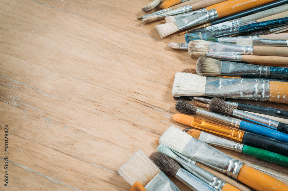 Fototapeta premium Bunch of old artist paintbrushes on wooden rustic table with space for text