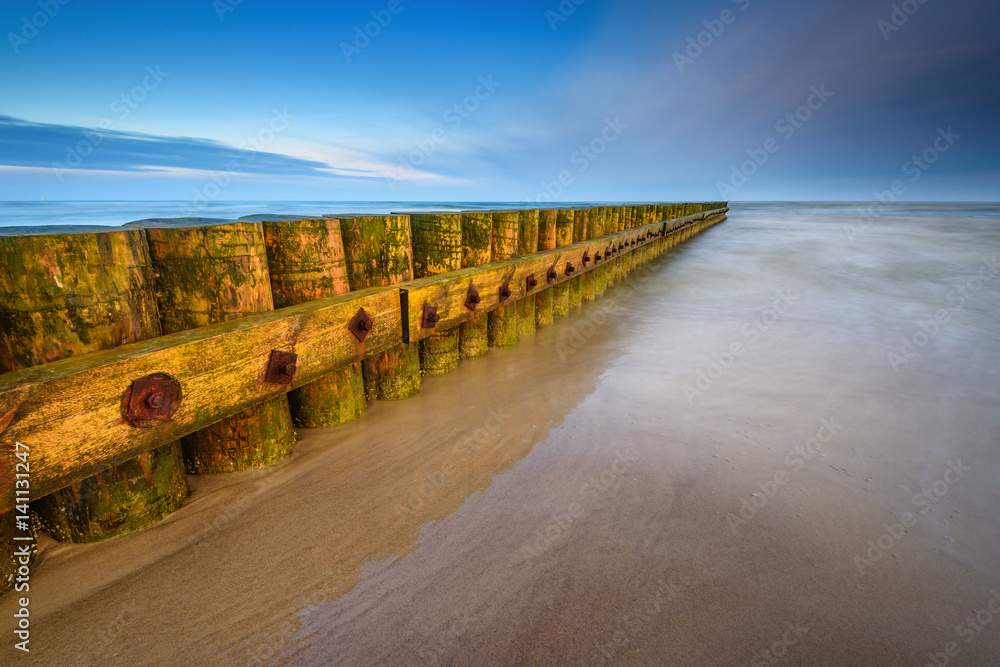 A breakwater on a sandy beach in Leba, Poland, Europe. Baltic sea.	