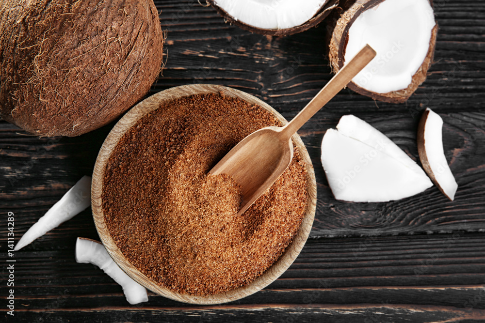 Bowl and scoop of brown sugar with coconut on wooden background Bowl and scoop of brown sugar with coconut on wooden background