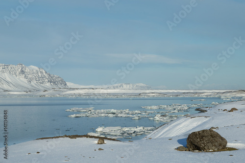 glacial ice floating in a glacial lagoon surrounded by mountains, Iceland