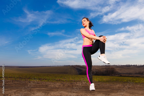 young woman doing exercises on blue sky background