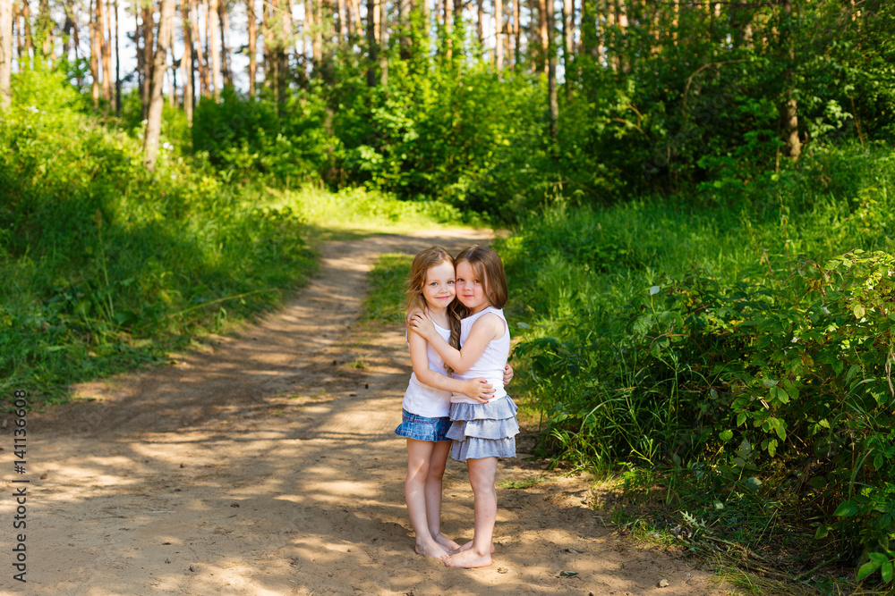 Two little girl girl friends hugging in the forest Two little girl girl friends hugging in the forest