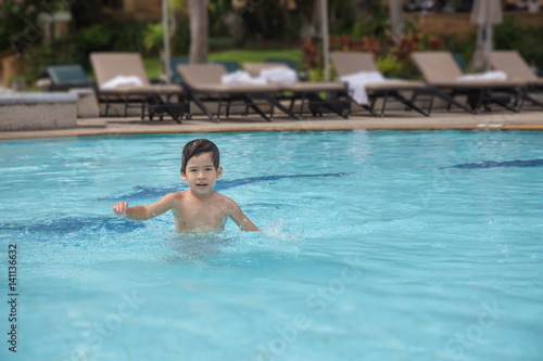 4 years old Asian kid swimming lonely in clean swimming pool at sport club