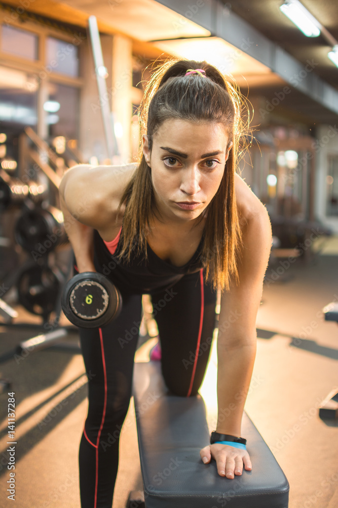 Obraz premium Sportswoman doing exercises with dumbbells in gym.