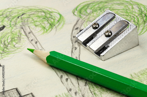 Green pencil and sharpener on the background of children's drawing