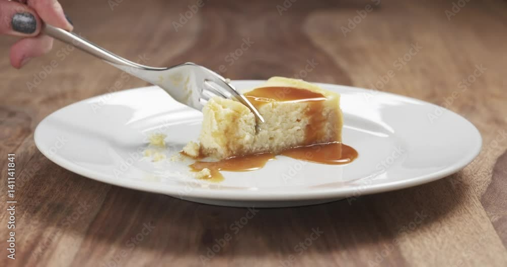 Slow motion of eating caramel cheesecake with fork on wood table, 4k 60fps prores footage Slow motion of eating caramel cheesecake with fork on wood table, 4k 60fps prores footage
