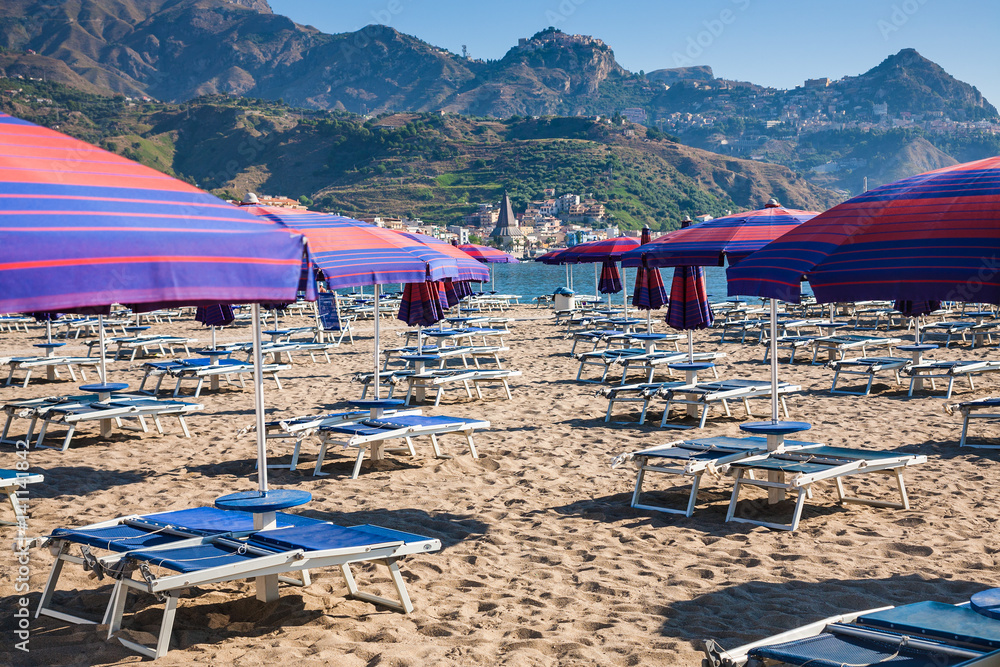 Parasols and beds on urban beach in giardini naxos