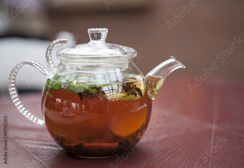 стеклянный чайник с чаем на деревянной поверхности стола