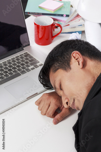 Businessman stressed and fall asleep on the tableat work on white background photo