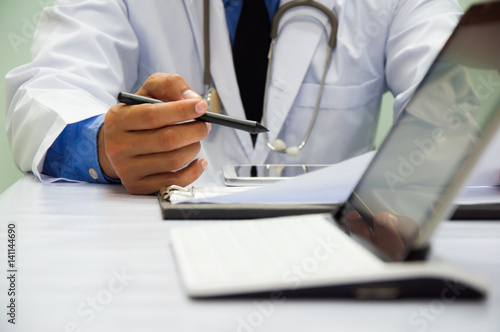 Medicine doctor working with computer notebook and digital tablet at desk in the hospital