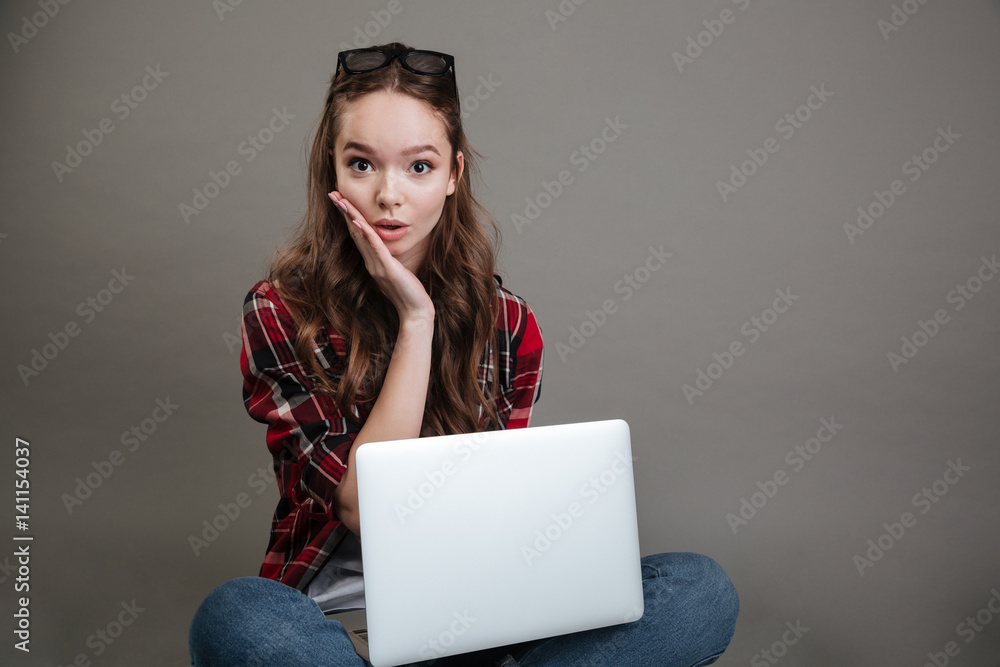 © Drobot Dean - Surprised young lady chatting by laptop computer.