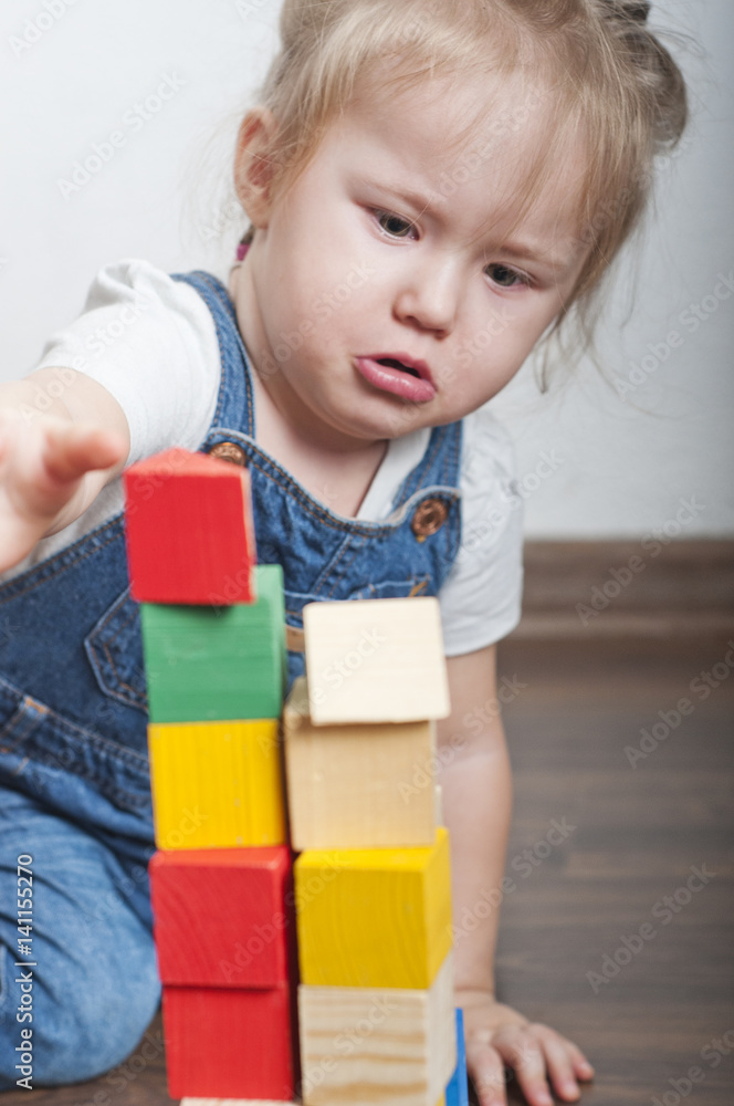 Little cute girl playing with a wooden constructor Little cute girl playing with a wooden constructor