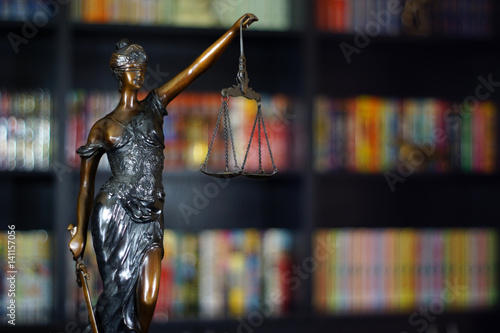 Goddess of justice statue in lawyer cabinet on bookshelf background