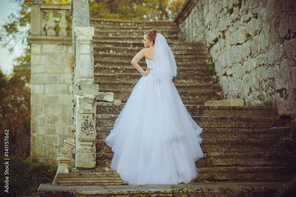 Beautiful bride walking near old castle before wedding ceremony Beautiful bride walking near old castle before wedding ceremony