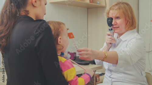 Optometrist checks child's eyesight - mother and child in ophthalmologist room