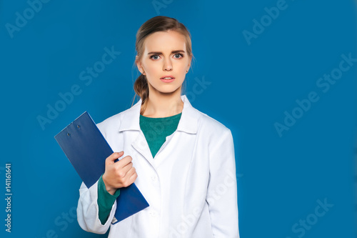 Young female student doctor with a tablet on a blue background showing signs