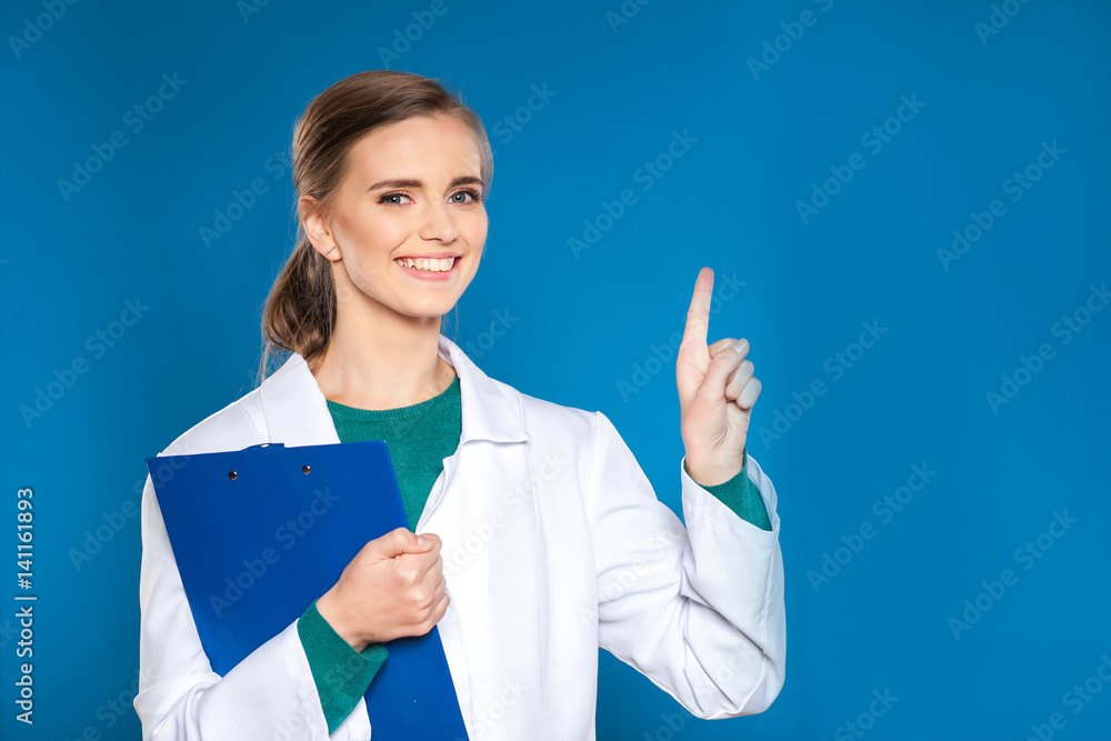 Young female student doctor with a tablet on a blue background showing signs