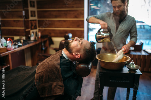Man at barbershop, barber pours water into a bowl
