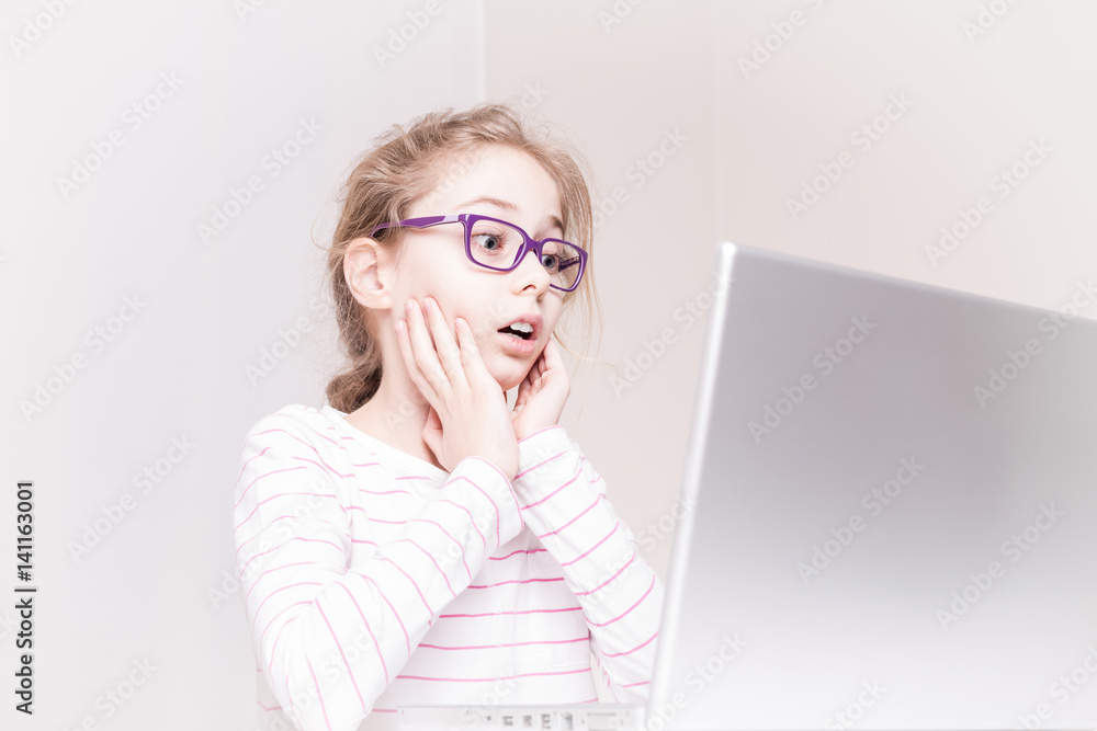 Surprised and shocked child girl (kid) using laptop computer Surprised and shocked child girl (kid) using laptop computer