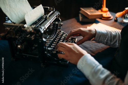 Literature author in glasses typing on typewriter