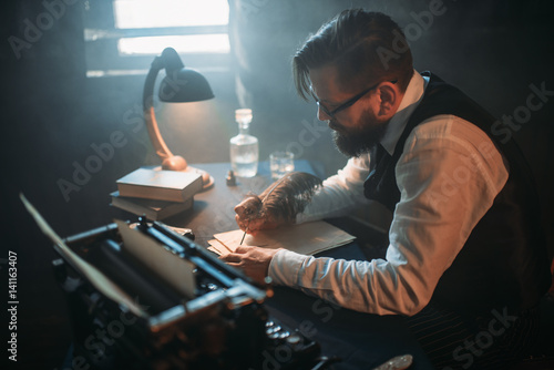 Writer in glasses writes novel with a feather