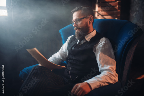 Bearded writer in glasses reads handwritten text