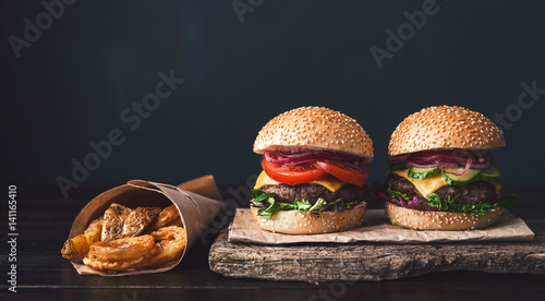 Obraz na płótnie two mouth-watering, delicious homemade burger used to chop beef. on the wooden table. w salonie