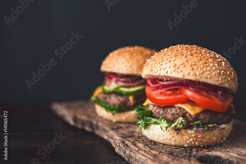 two mouth-watering, delicious homemade burger used to chop beef. on the wooden table.