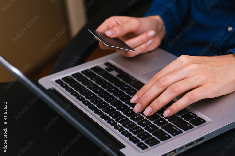 Woman's hands holding a credit card and using laptop for online shopping Woman's hands holding a credit card and using laptop for online shopping