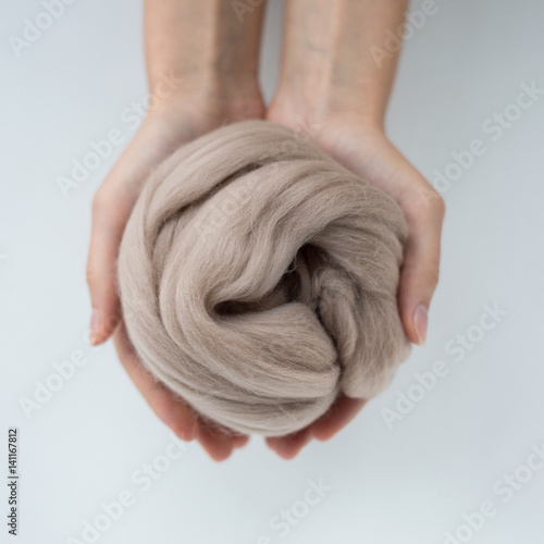 Close-up of brown merino wool ball in hands. photo