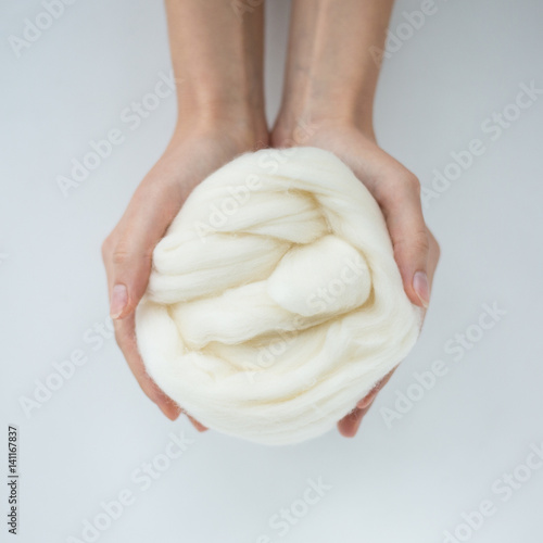 Close-up of white merino wool ball in hands. photo
